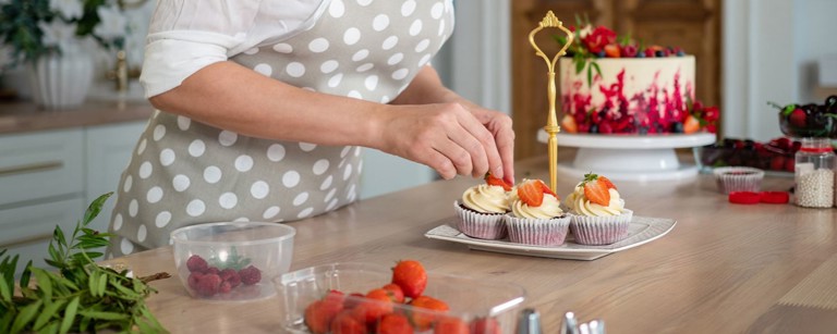 Frau dekoriert cupcakes mit Erdbeeren